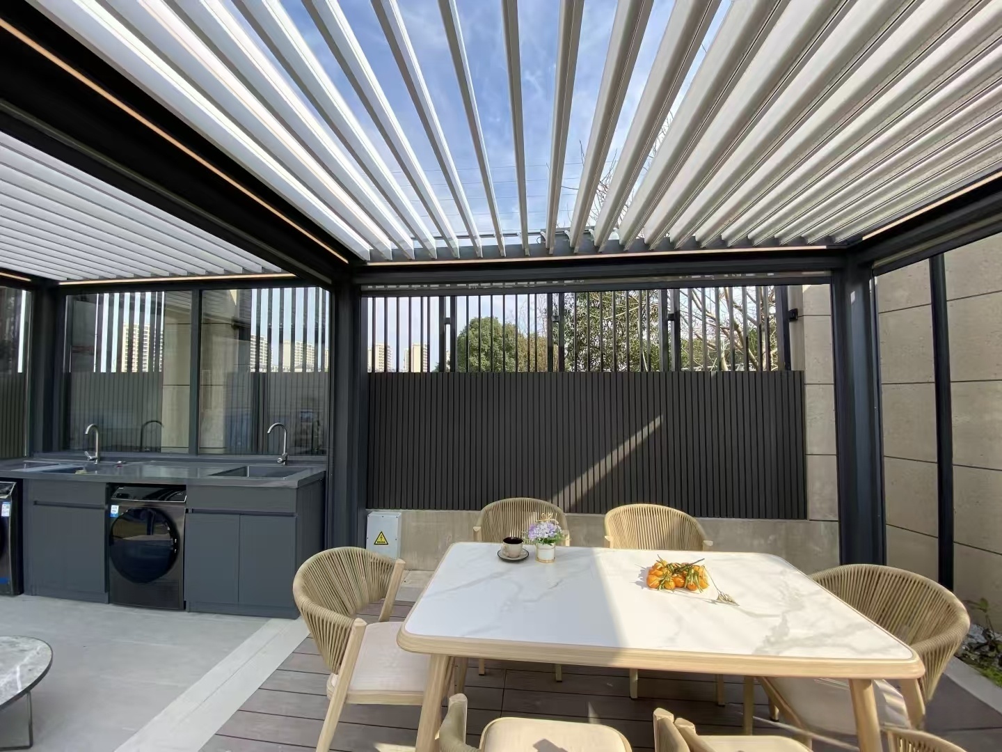 Open aluminum pergola louvers admitting daylight above an outdoor dining area