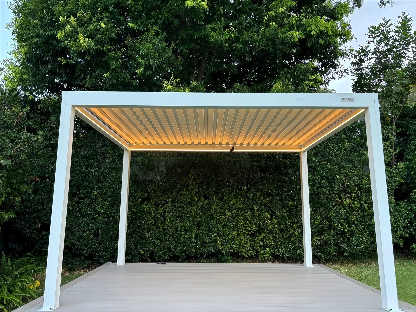 White freestanding louvered pergola installed independently in a garden