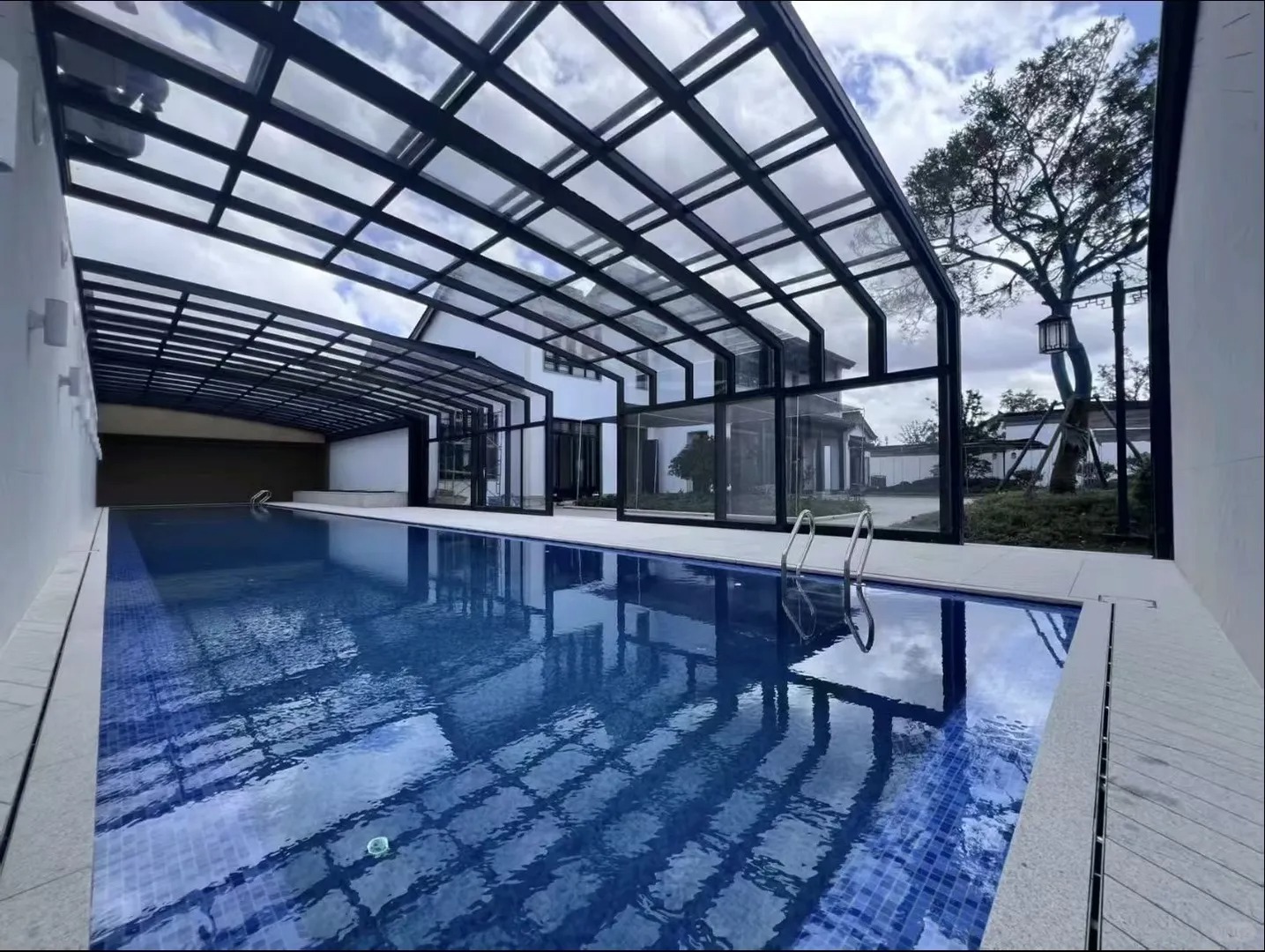 Retractable sunroom enclosing a swimming pool with an open section and views to the garden