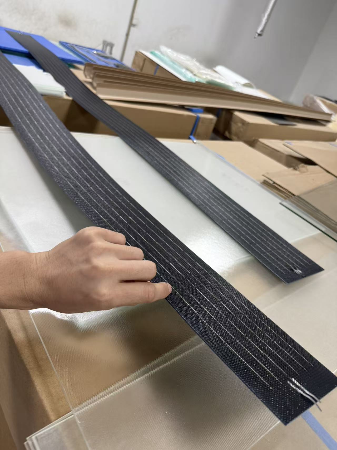 Flexible strip-shaped solar panel material prepared for integration into pergola louvers