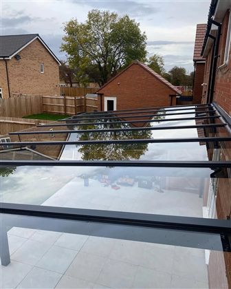 Glass-roof aluminum patio cover attached to a UK brick home